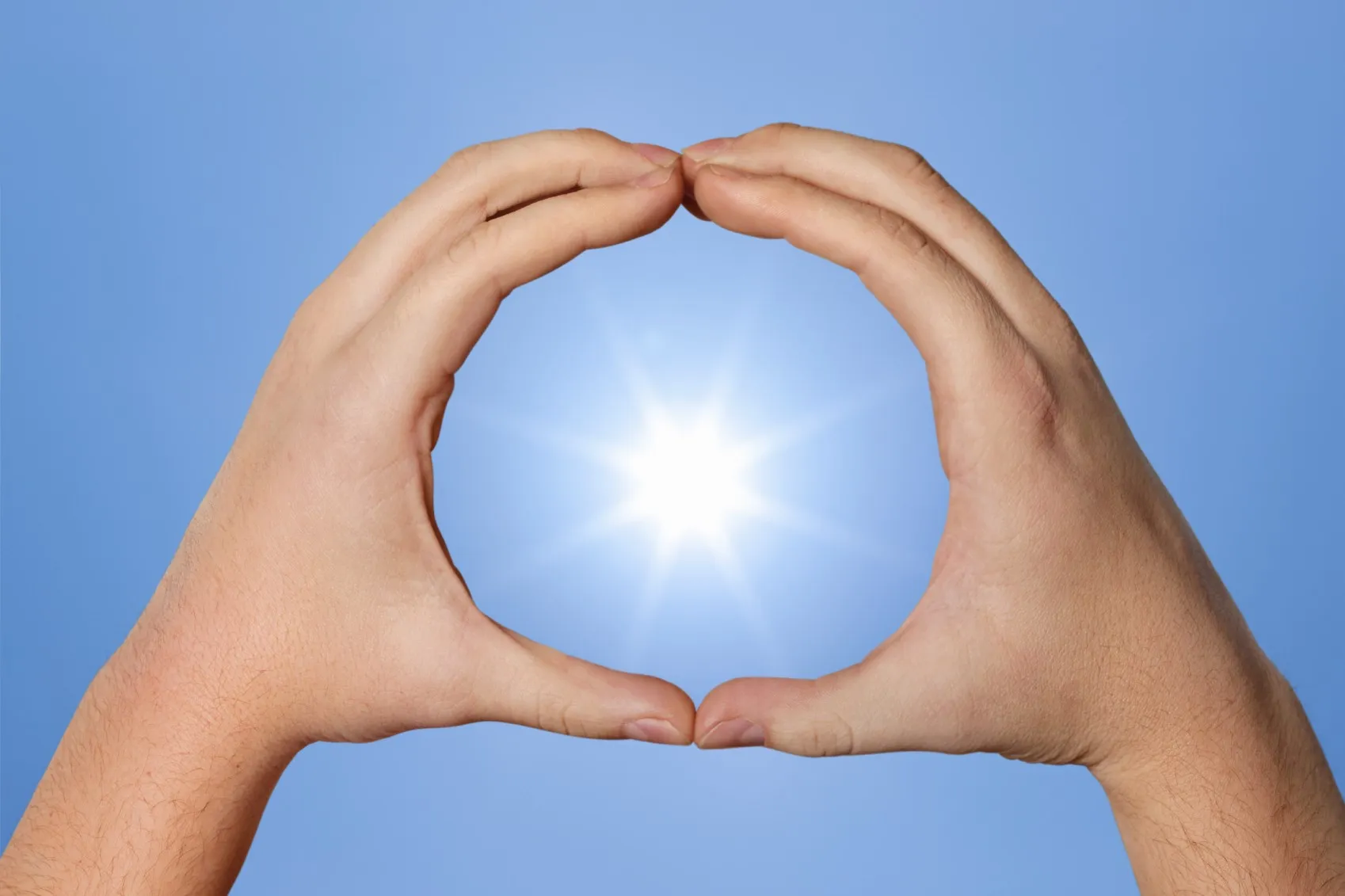 Zwei Hände formen einen Kreis vor der Sonne