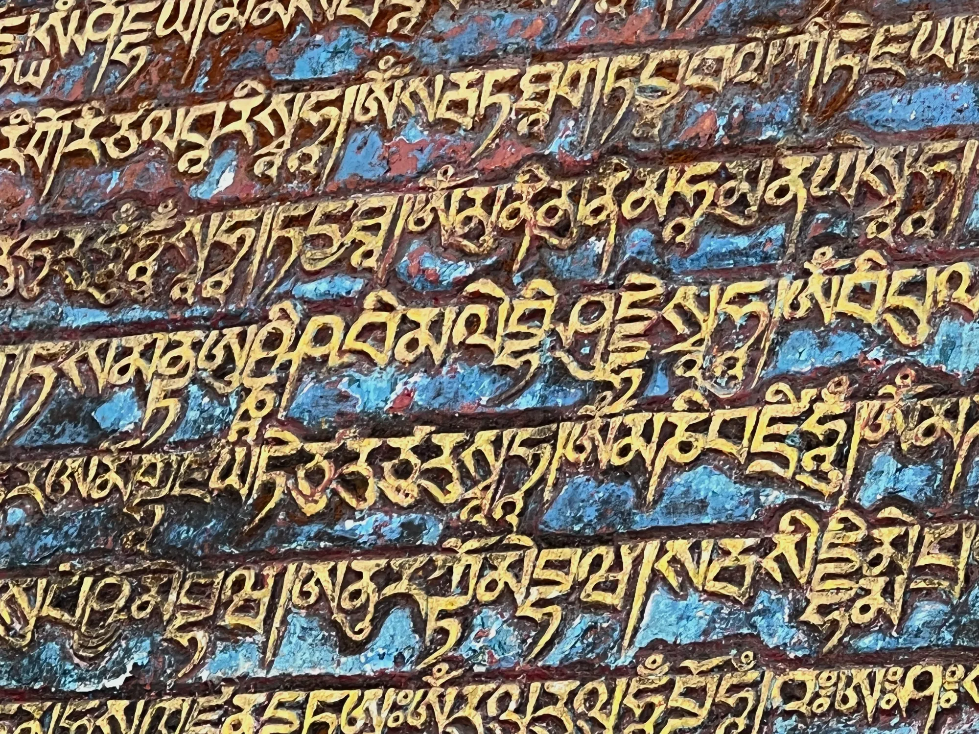 Goldene tibetische Schriftzeichen auf blauem Stein